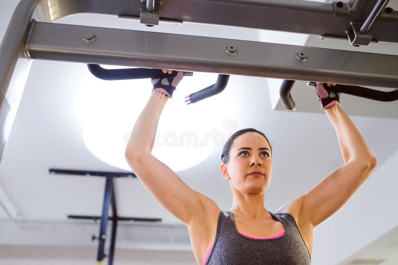 Woman in gym doing arms exercises on a machine
