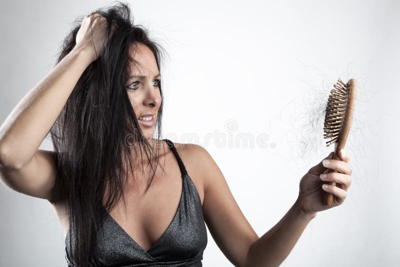 Attractive young woman with hair loss and hairbrush