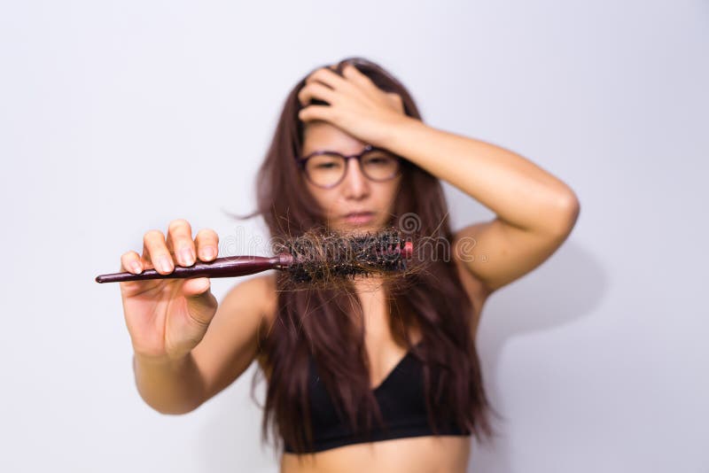 Woman with hair loss holding comb. Young girl losing hair probl stock photo Woman with hair loss holding comb. Young girl losing hair probl stock photo