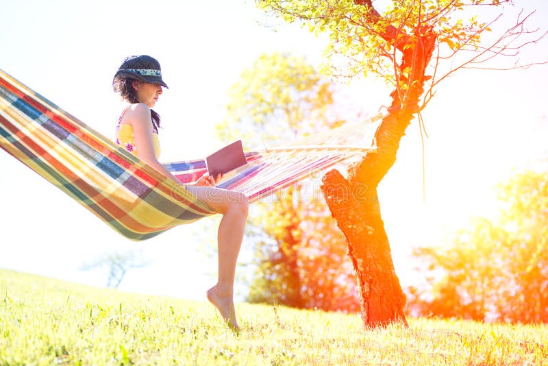 Woman on hammock reading a book in spring