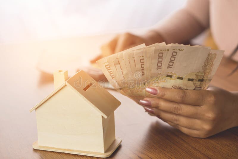 Woman hand calculating money with house model on wooden table planing to buy or rent home