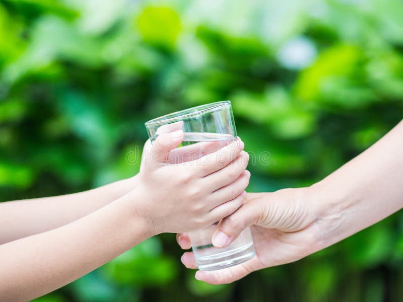 Woman hand giving glass of fresh water to child royalty free stock photography Woman hand giving glass of fresh water to child royalty free stock photography