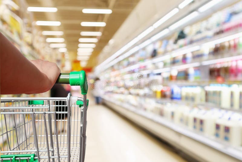 Woman hand hold supermarket shopping cart with abstract blur refrigerator shelves stock photos Woman hand hold supermarket shopping cart with abstract blur refrigerator shelves stock photos