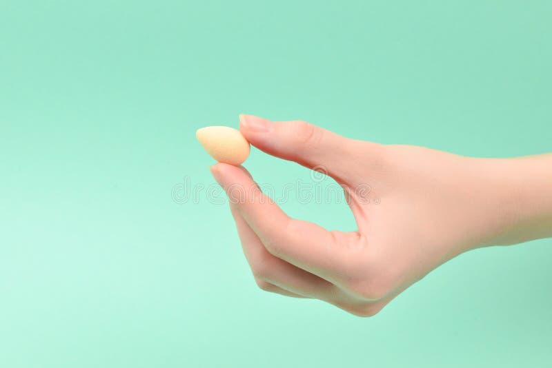 Woman hand holding beauty sponge on green background stock photos Woman hand holding beauty sponge on green background stock photos