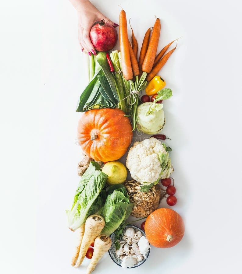 Woman hand holding heap of fresh organic seasonal vegetables with pumpkin and fruits on white background. Top view. Autumn harvest