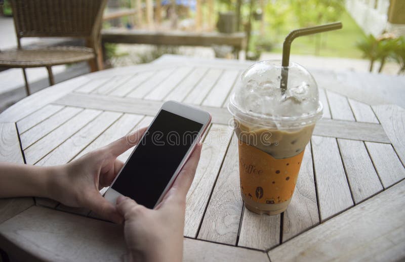 Woman hand holding a smartphone with isolate black screen,at coffee cafe,selective focus,light effect added stock photos