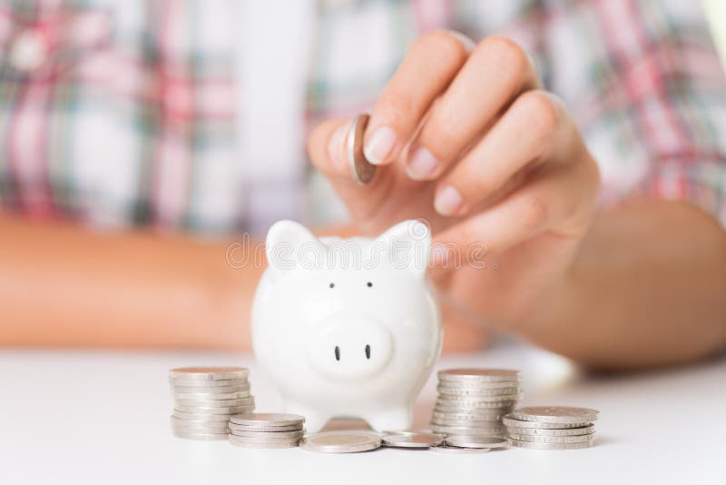 Woman hand putting money coin into piggy bank and stack of coins stock image Woman hand putting money coin into piggy bank and stack of coins stock image