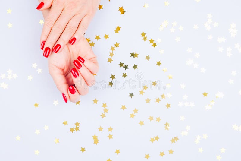 Woman hand with red manicure on blue background with sprinkles. stock photography Woman hand with red manicure on blue background with sprinkles. stock photography