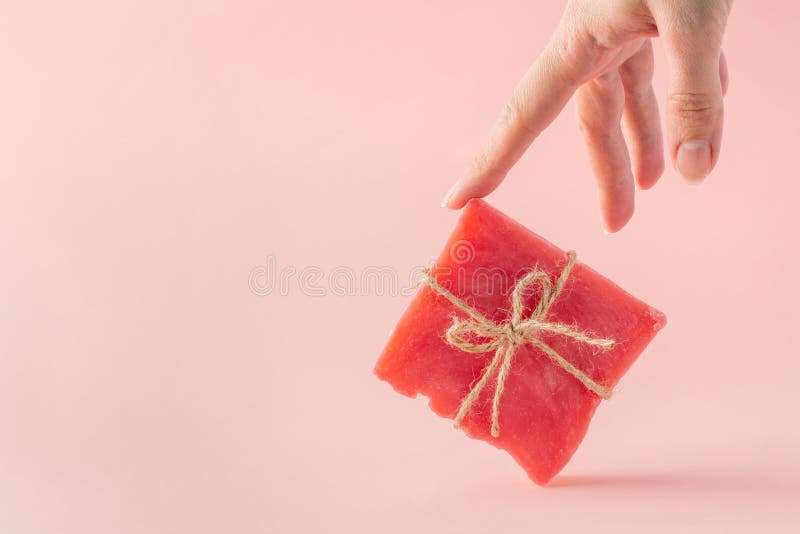 Woman hand supports a pink soap bar