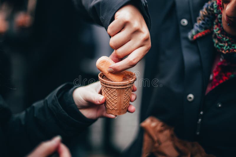 Una mujer manos comer líquido sobre el El mercado en, alemania cabanas a estable muchos de pie en multitudes bebiendo soldado vino a caliente.