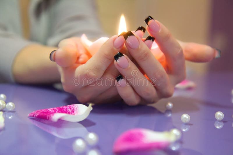 Woman hands with french manicure holding a candle stock photo Woman hands with french manicure holding a candle stock photo