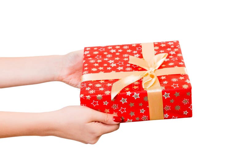 Woman hands give wrapped Christmas or other holiday handmade present in red paper with Gold ribbon. Isolated on white background