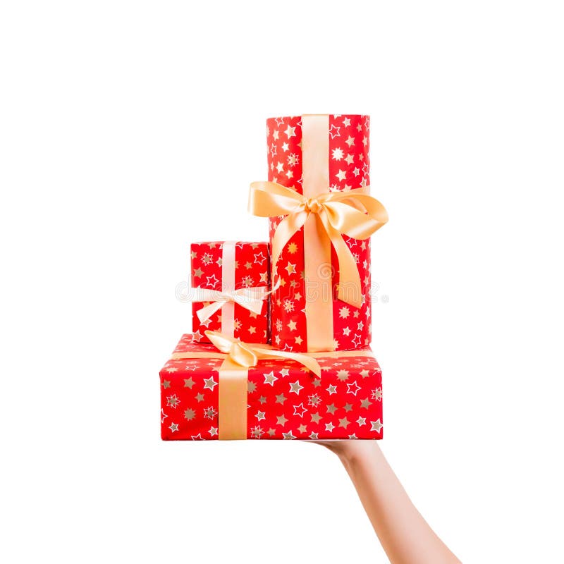 Woman hands give wrapped group of Christmas or other holiday handmade present in red paper with Gold ribbon. Isolated on white