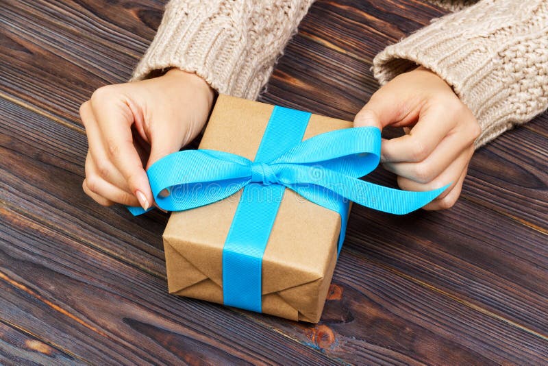 Woman hands give wrapped valentine or other holiday handmade present in pap...