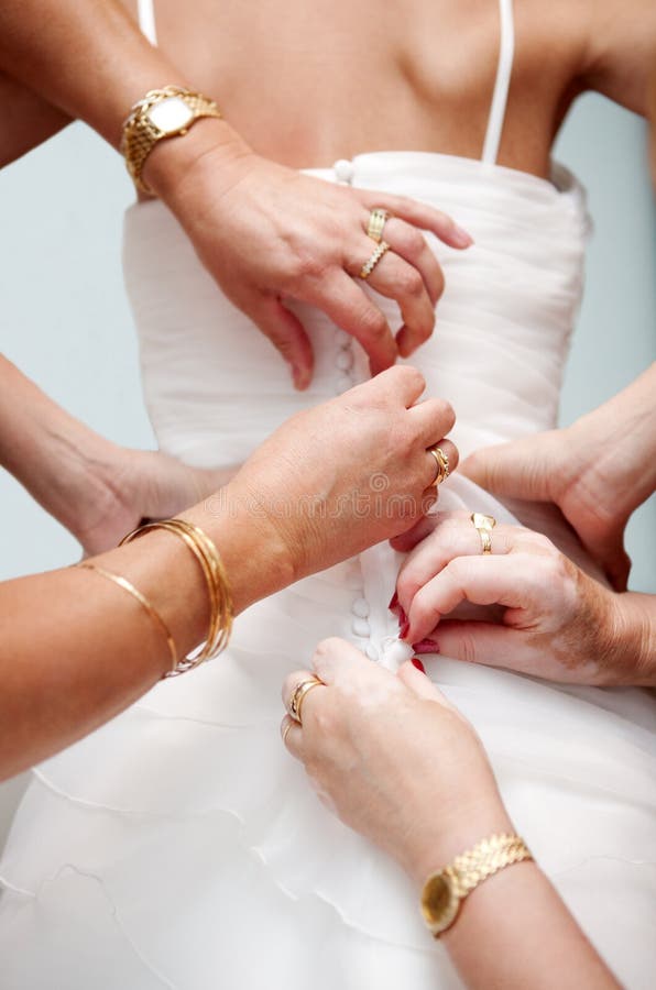 Woman hands help the bride to button the elegant wedding dress