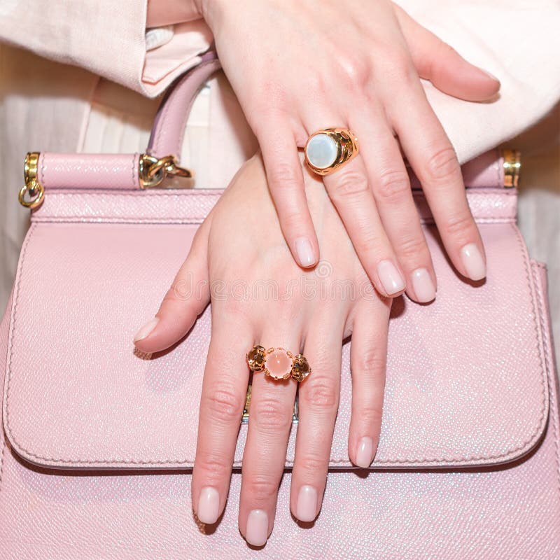 Woman hands with manicure and luxury jewelry rings. Close up of trendy leather pink bag with female hands showing stock images Woman hands with manicure and luxury jewelry rings. Close up of trendy leather pink bag with female hands showing stock images