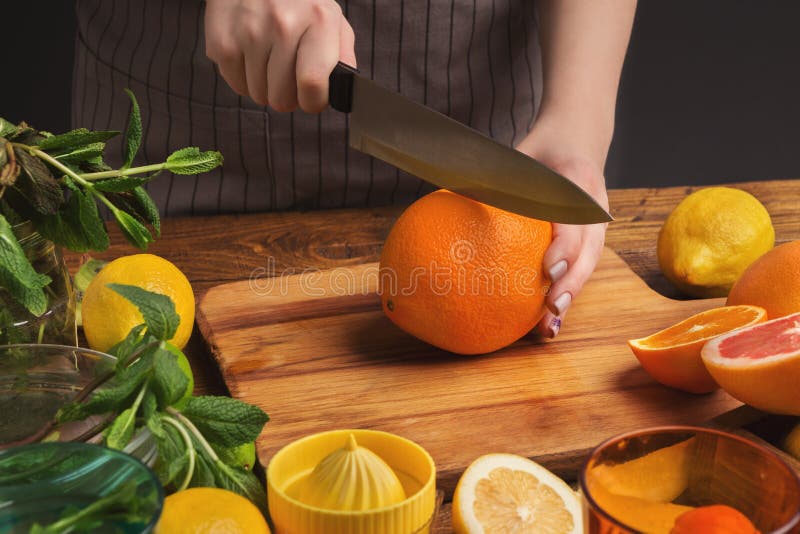 Female hands cutting citrus fruits on wooden board