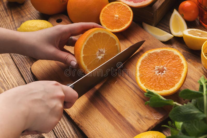 Female hands cutting citrus fruits on wooden board