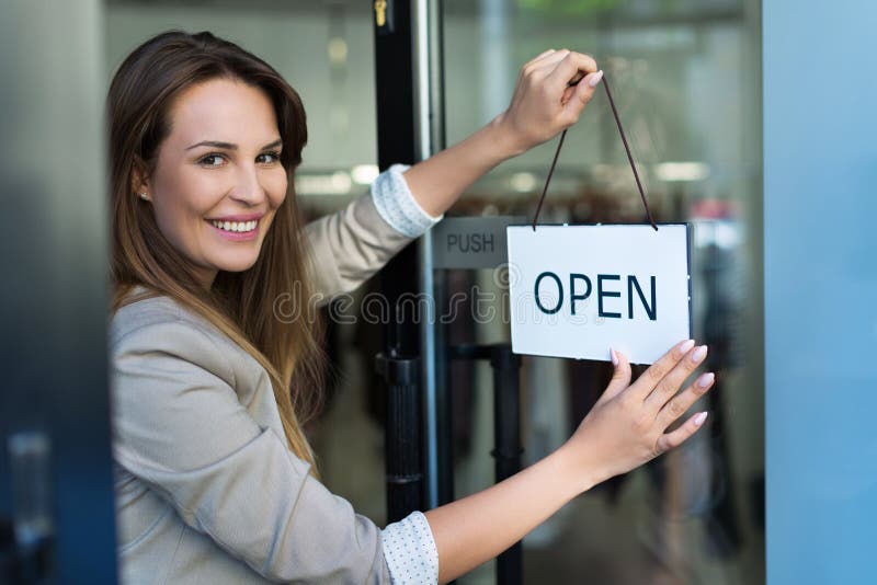 Woman hanging open sign on door royalty free stock photo