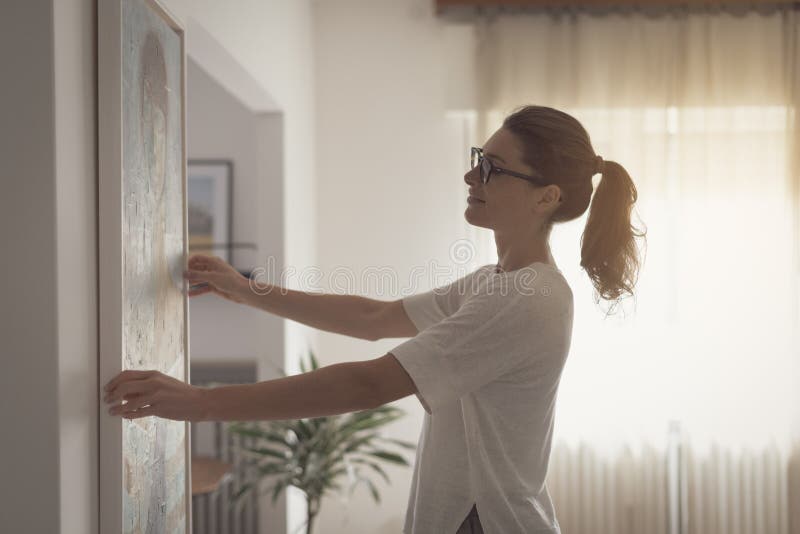 Woman hanging a painting at home