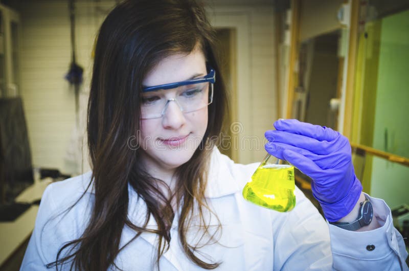 Woman happy scientist holding and paying attention skillful yellow chemical reaction in chemistry laboratory for science