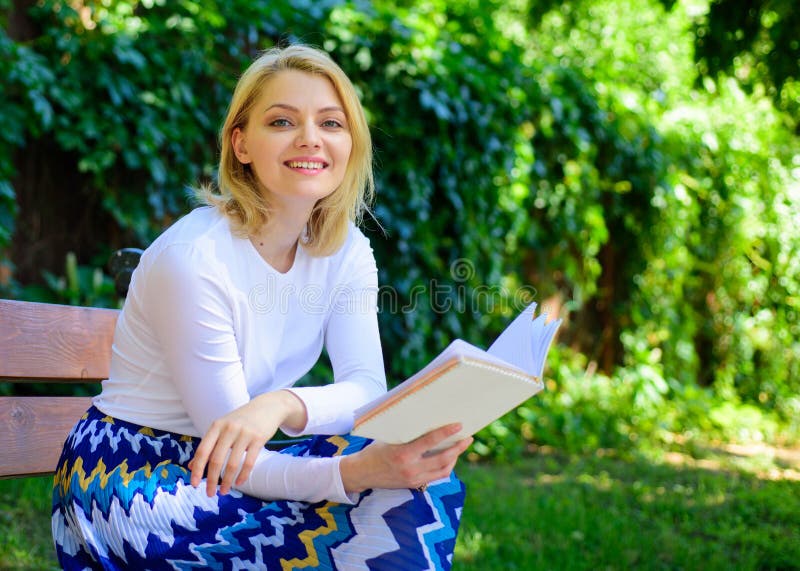 Woman happy smiling blonde take break relaxing in garden reading book. Girl sit bench relaxing with book, green nature background. Lady enjoy self imrovement and education. Improve your knowledge.