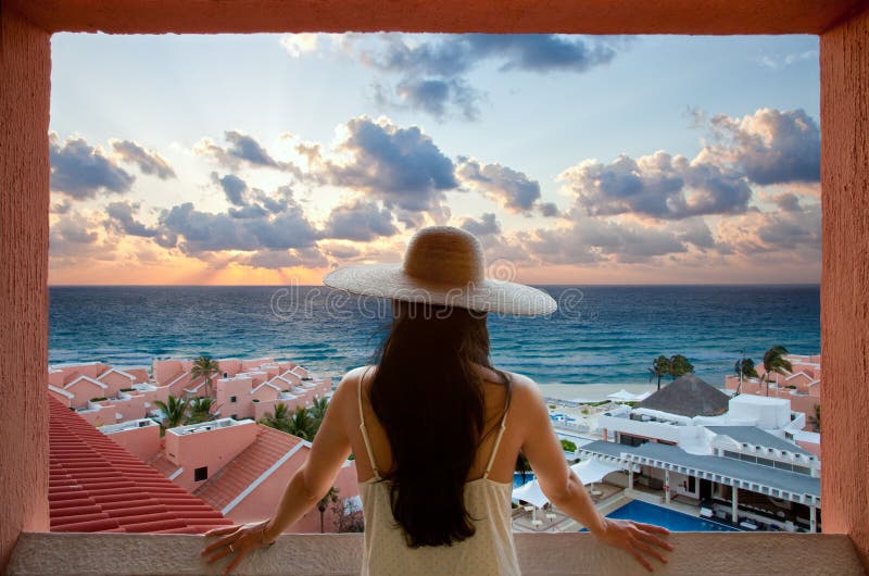 Woman with hat looking at the beach and sky