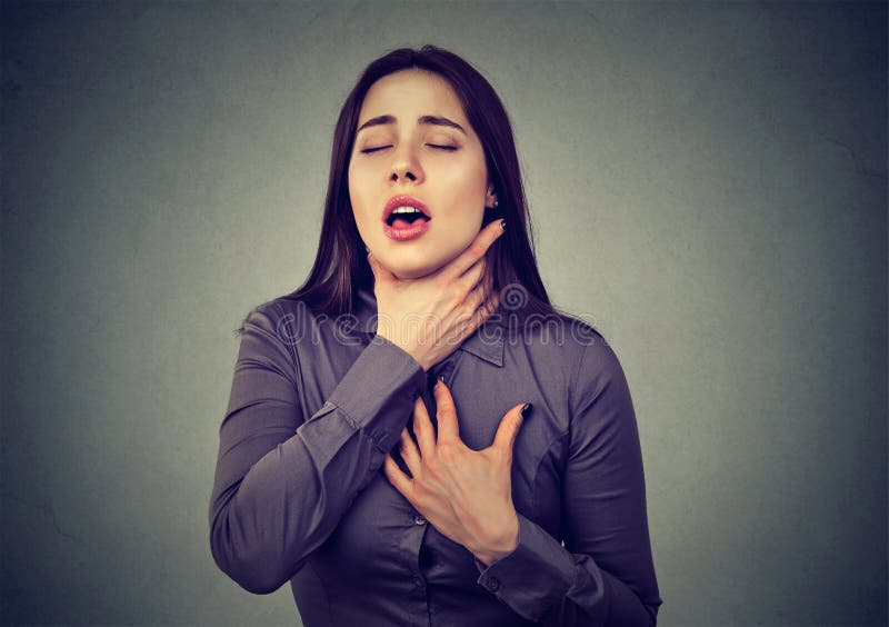 Young woman having asthma attack or choking can`t breath suffering from respiration problems on gray background