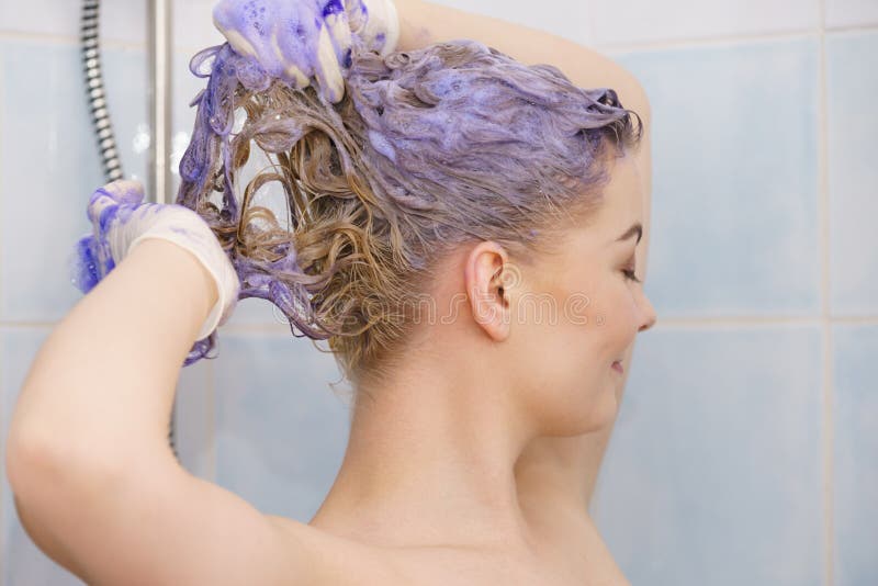 Woman under the shower with colored foam on hair