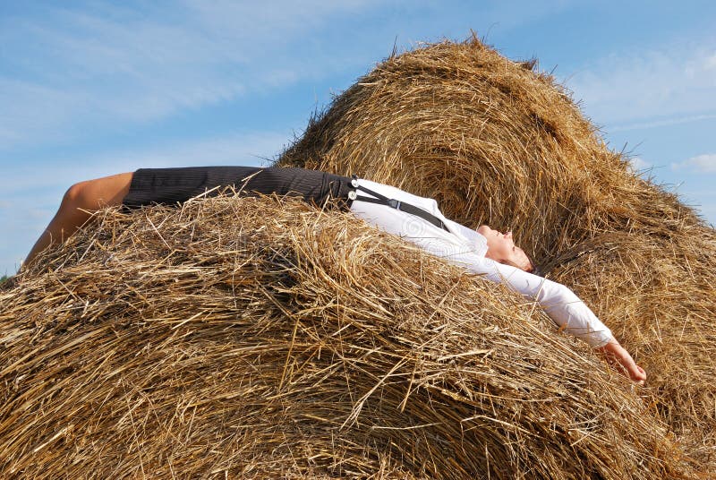 Woman on hay bale in summer field enjoying a warm windy day