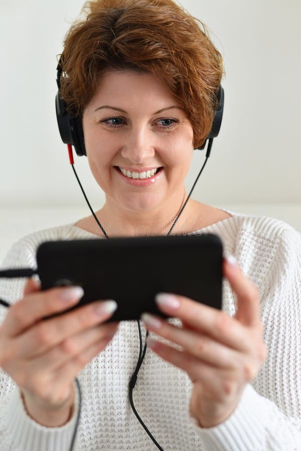 Woman in headphones holding smartphone royalty free stock photos Woman in headphones holding smartphone royalty free stock photos