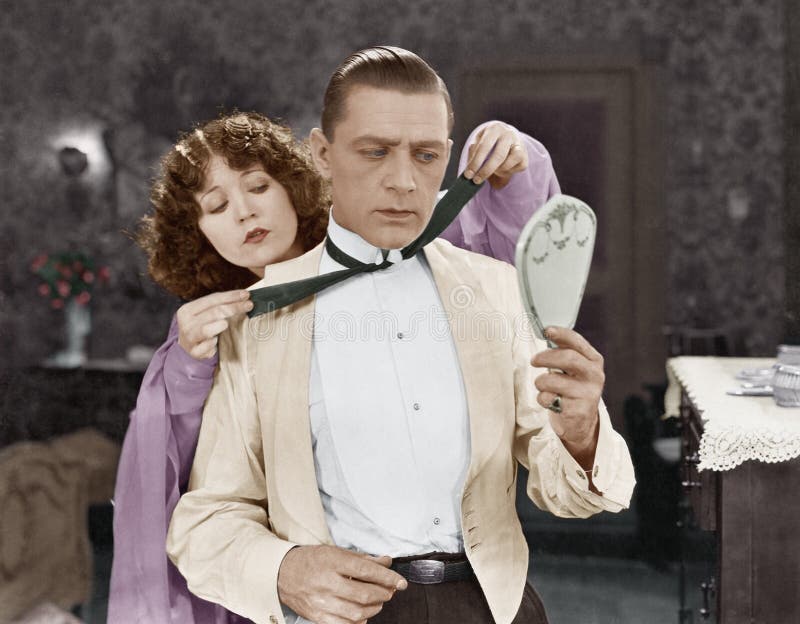 Woman helping man tie bow tie (All persons depicted are no longer living and no estate exists. Supplier grants that there will be no model release issues. ). Woman doubtful looking stock images, royalty-free photos and pictures