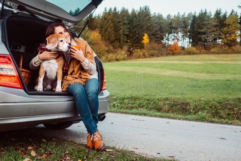 Woman with her dog have a tea time during their autumn auto travel