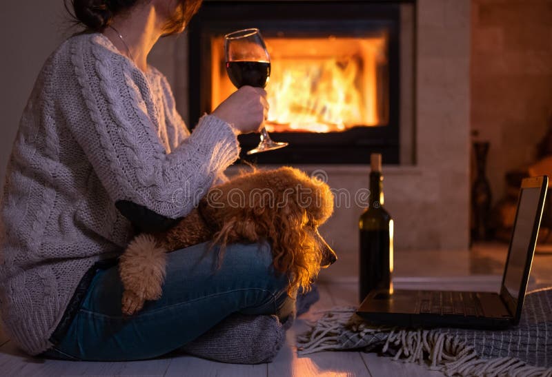 Woman with her dog sits at the floor and drinking wine