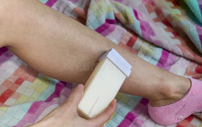Woman and her hairy leg on a multi-colored towel. Girl carries out the procedure of depilation by wax royalty free stock photo Woman and her hairy leg on a multi-colored towel. Girl carries out the procedure of depilation by wax royalty free stock photo