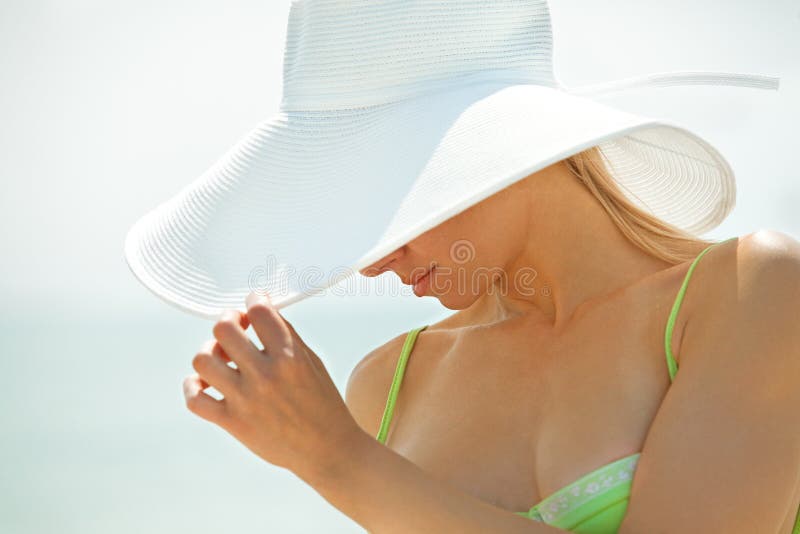 Woman hiding her face behind her white hat