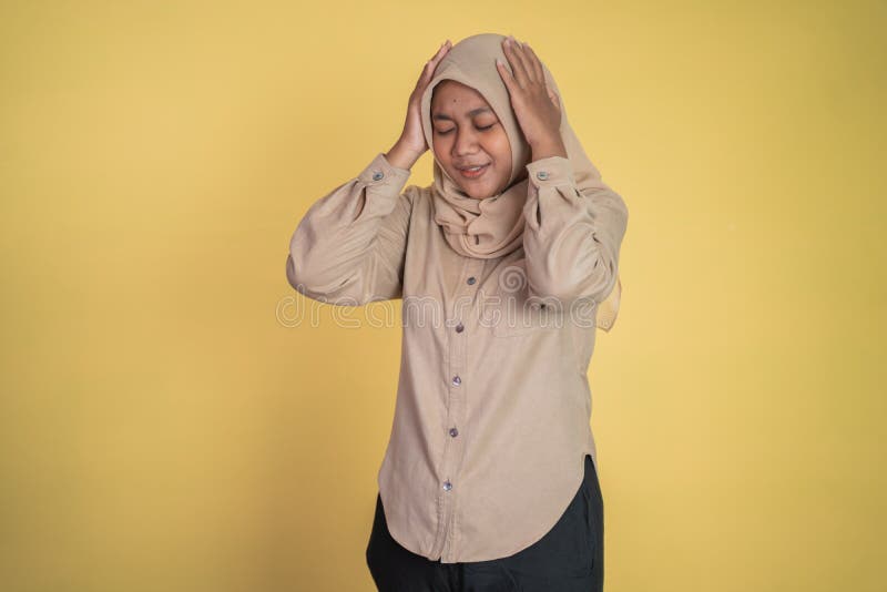 Woman in hijab holding head while confused by situation on isolated background