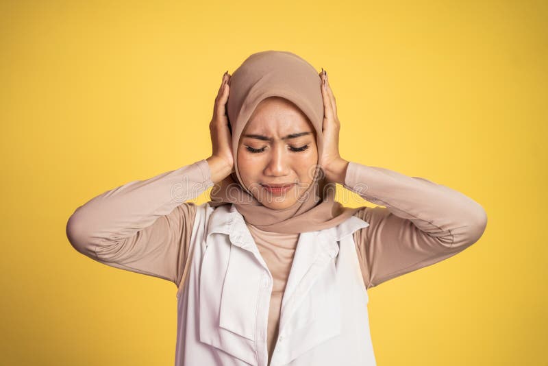 Woman in hijab holding head while confused by situation on isolated background cover her ear