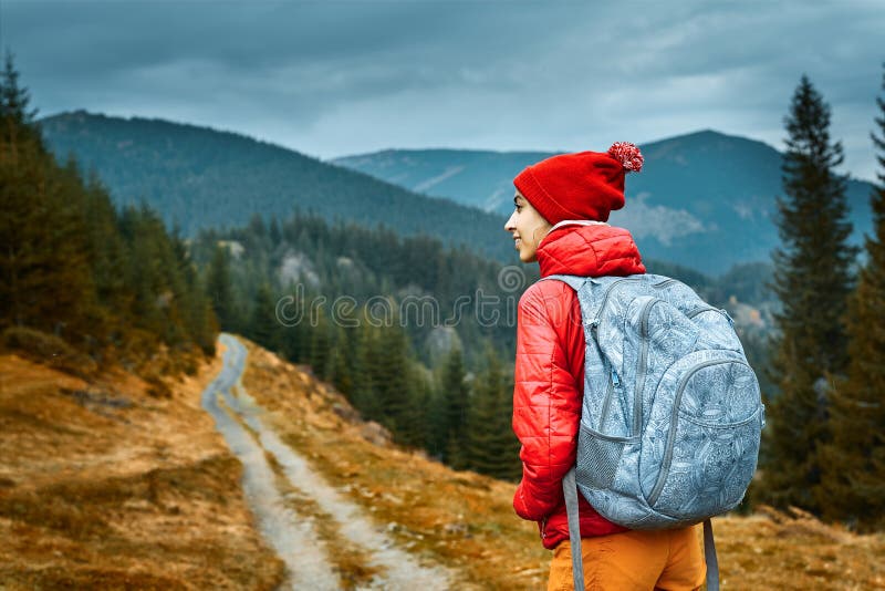 Woman hiker with backpack, wearing in red jacket and orange pants, standing on the mountains background royalty free stock images Woman hiker with backpack, wearing in red jacket and orange pants, standing on the mountains background royalty free stock images