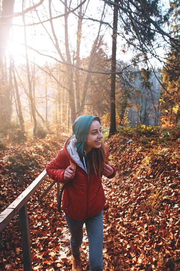 Woman hiker with backpack wearing in red jacket is walking through a foggy autumn woods at the morning and enjoying the stock images Woman hiker with backpack wearing in red jacket is walking through a foggy autumn woods at the morning and enjoying the stock images