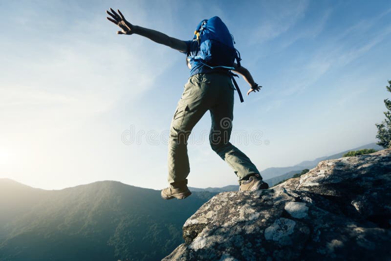 Brave woman hiker walking to the cliff edge on mountain top