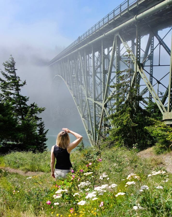 Woman hiking by ocean in foggy morning.