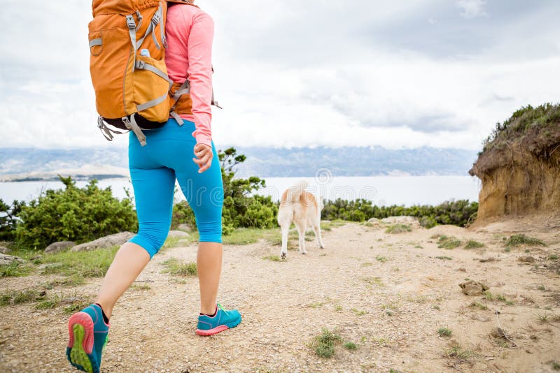 Woman hiking with akita inu dog on seaside trail. Recreation and healthy lifestyle outdoors in summer mountains and sea nature. Beautiful inspirational landscape. Trekking and activity concept. Woman hiking with akita inu dog on seaside trail. Recreation and healthy lifestyle outdoors in summer mountains and sea nature. Beautiful inspirational landscape. Trekking and activity concept.