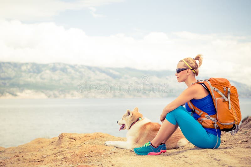 Woman hiking with akita inu dog on seaside trail. Recreation and healthy lifestyle outdoors in summer mountains and sea nature. Beautiful inspirational landscape. Trekking and activity concept. Woman hiking with akita inu dog on seaside trail. Recreation and healthy lifestyle outdoors in summer mountains and sea nature. Beautiful inspirational landscape. Trekking and activity concept.