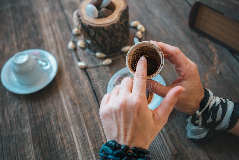 Woman hold the mug and telling fortune with traditional turkish coffee cup.