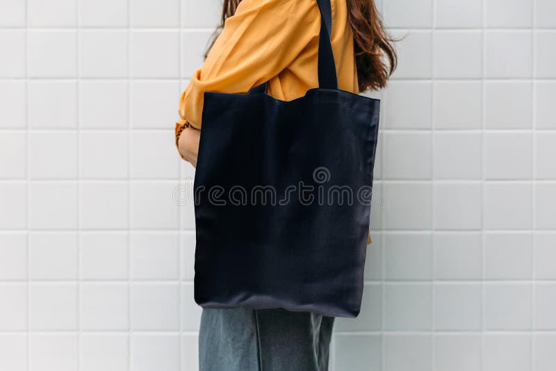 Woman is holding black bag canvas fabric for mockup blank template