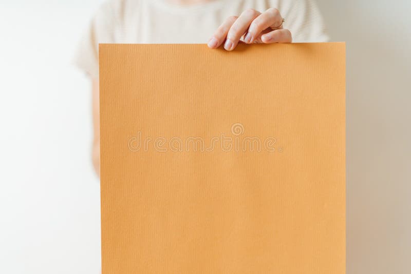 A woman holding blank orange paper poster or board. Indoors studio lifestyle stock image A woman holding blank orange paper poster or board. Indoors studio lifestyle stock image