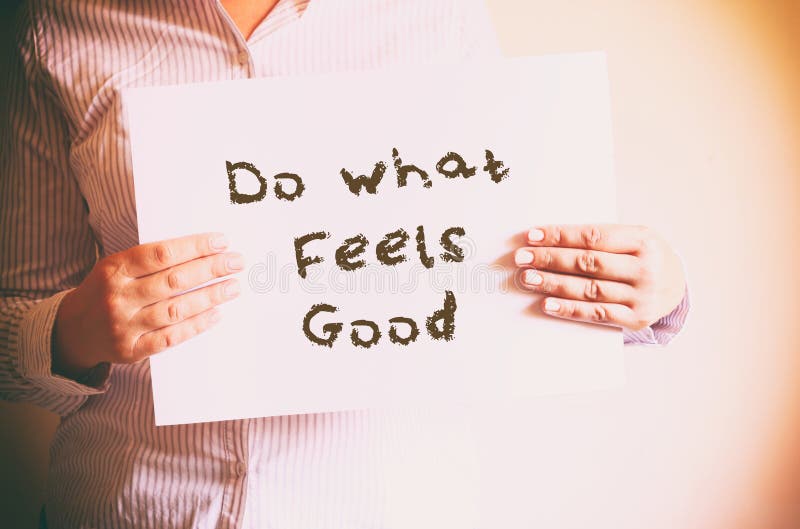 Woman holding board with the phrase do what feels good written on it. retro filtered image royalty free stock photography Woman holding board with the phrase do what feels good written on it. retro filtered image royalty free stock photography