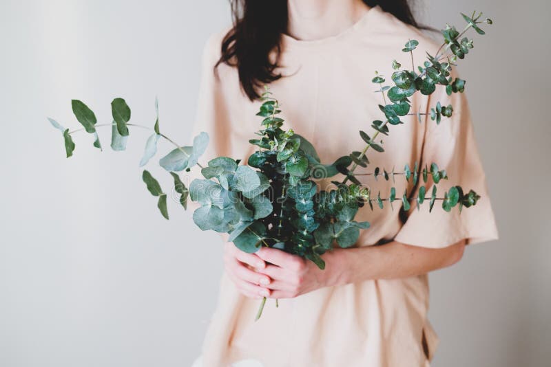 Woman holding bouquet made of eucalyptus green branches in her hands