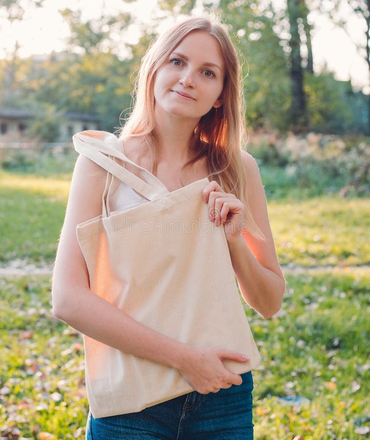 Woman holding canvas tote bag on nature background. Eco friendly concept. Outdoors